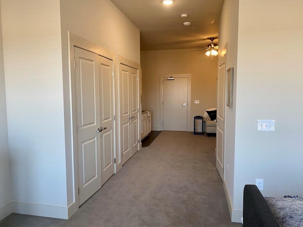 A hallway with a lot of doors and a ceiling fan.