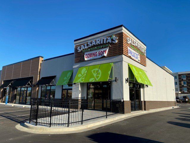The front of a salsarita 's restaurant with green awnings.