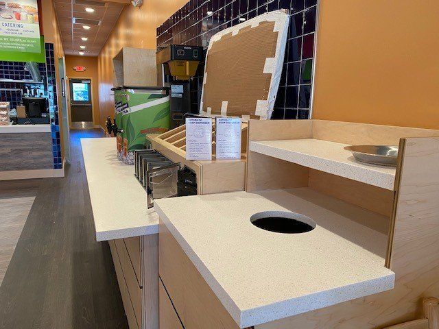 A counter in a restaurant with a trash can on it