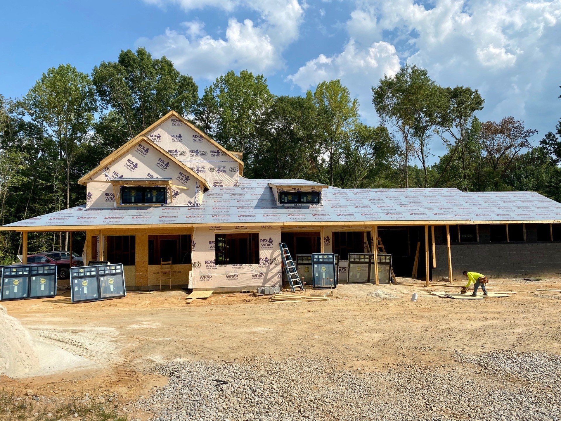 A large house is being built in the middle of a dirt field.