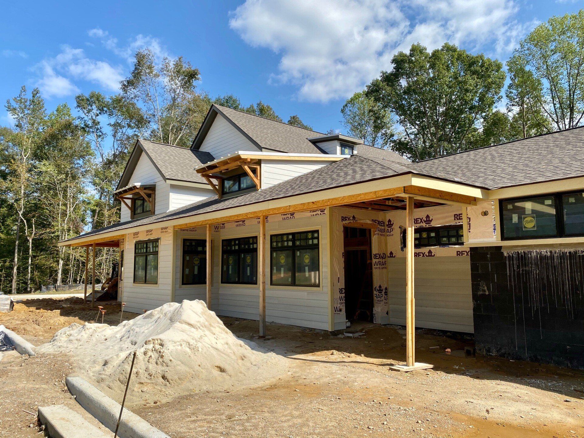 A large house is being built in the middle of a dirt field.