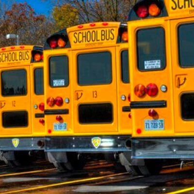 A row of school buses are parked next to each other in a parking lot.