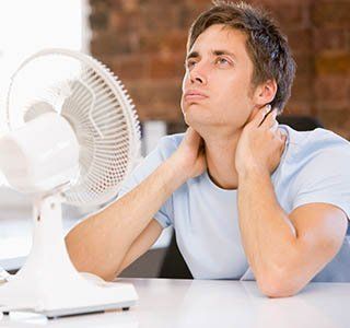 Man using an electric fan — Heating and Air Services in Amherst, NH Man using an electric fan — Heating and Air Services in Amherst, NH