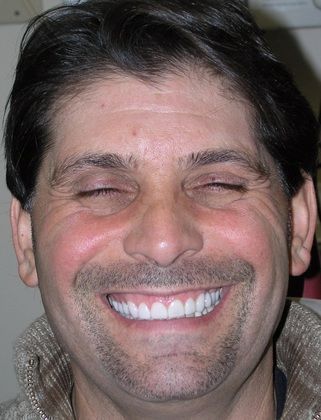 A man with a beard is smiling with his eyes closed.