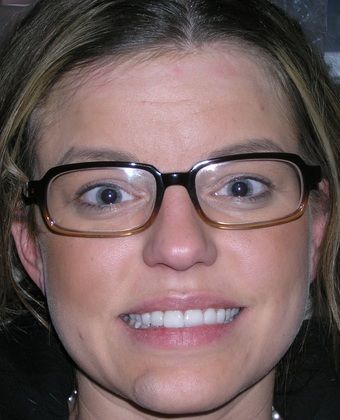 A close up of a woman wearing glasses and smiling.
