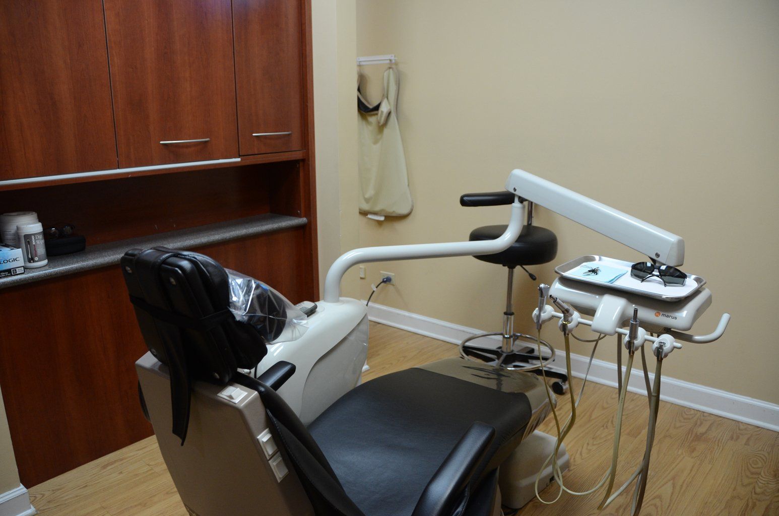 A dental chair in a dental office with a stethoscope on the wall.