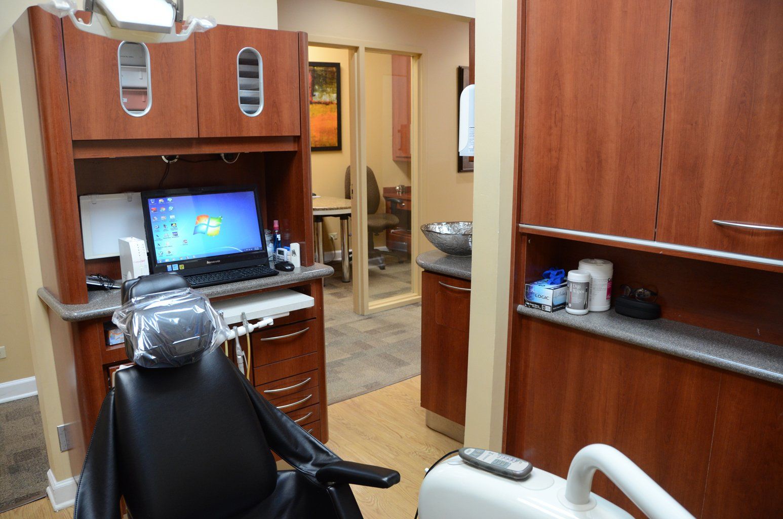A dental office with a dental chair and a computer on the desk.