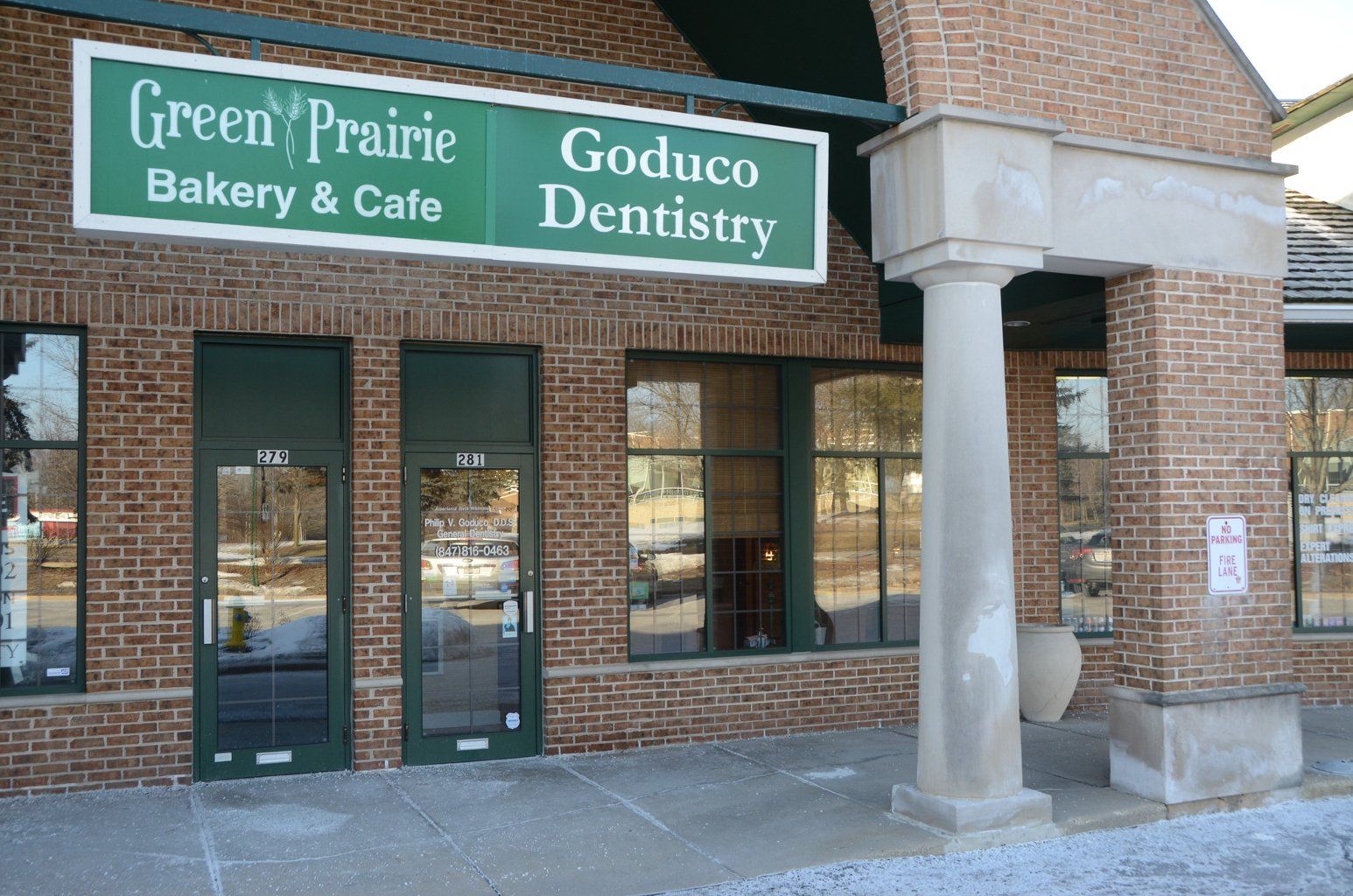 A brick building with a green sign that says green prairie bakery and cafe
