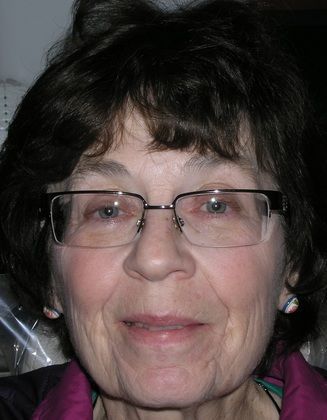 A close up of a woman wearing glasses and a purple jacket