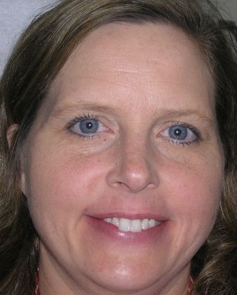 A close up of a woman 's face with blue eyes smiling.
