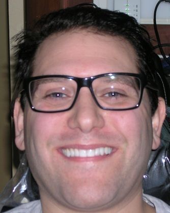 A man wearing glasses is smiling for the camera