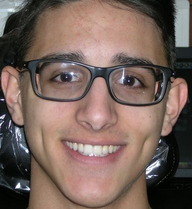 A young man wearing glasses is smiling for the camera