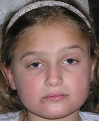 A young girl with a headband on her head is looking at the camera.