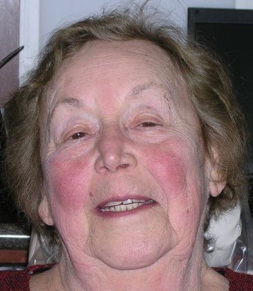 A close up of an elderly woman 's face with a smile on her face.