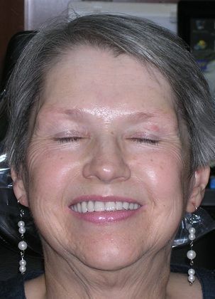 A close up of a woman 's face with her eyes closed and smiling.