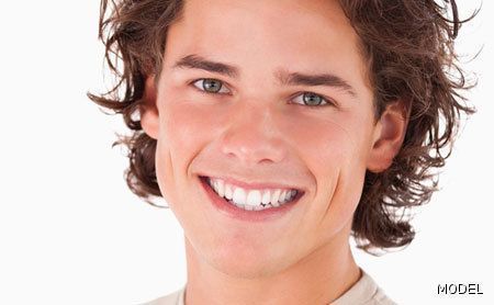 A young man with long hair is smiling for the camera.