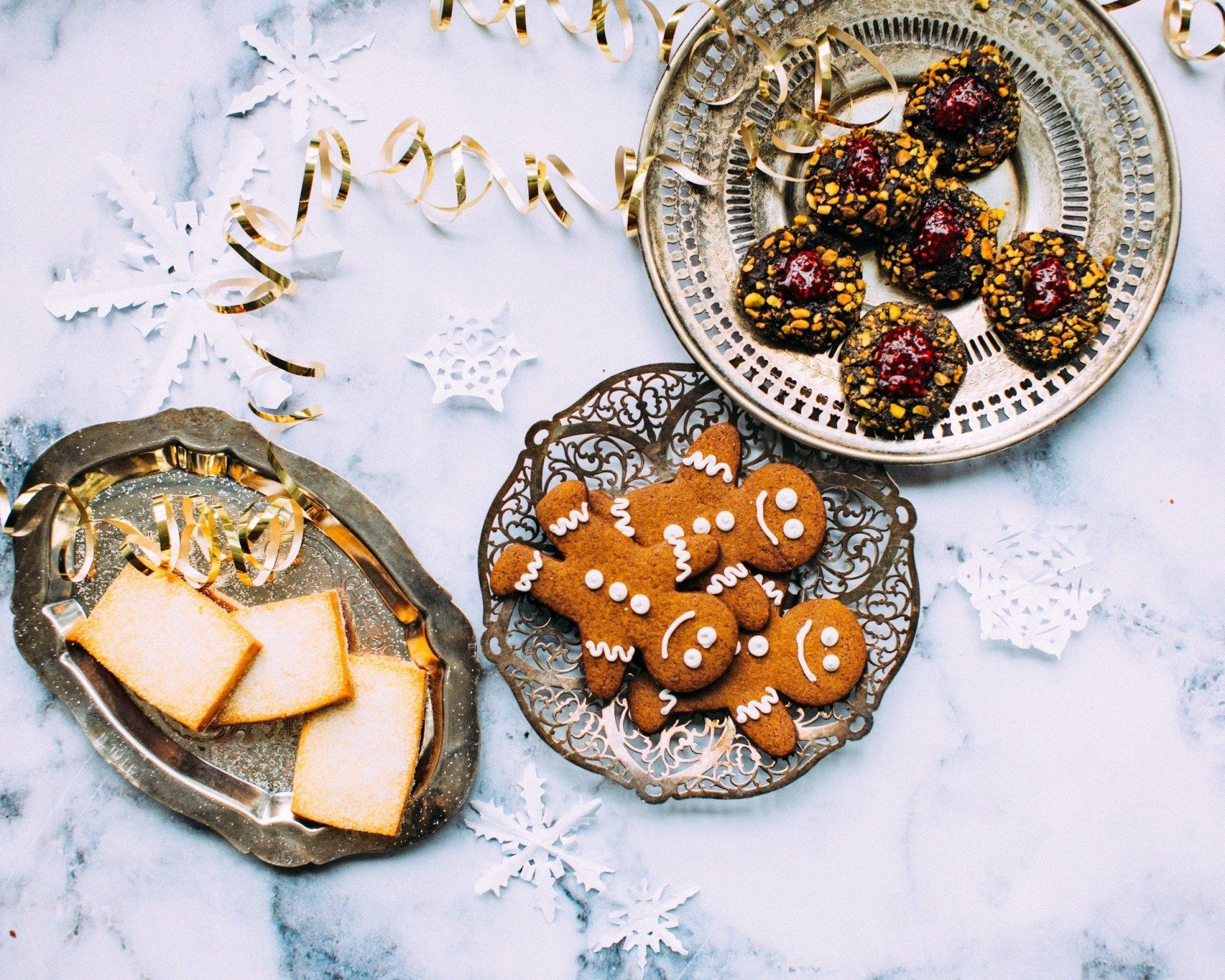 A table topped with plates of cookies including gingerbread men and chocolate balls.
