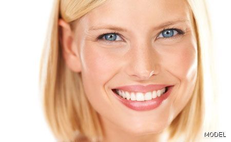 A close up of a woman 's face smiling on a white background.