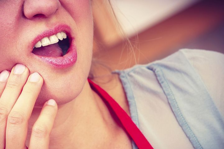 Person holding their cheek due to tooth pain before extraction in Vernon Hill, IL