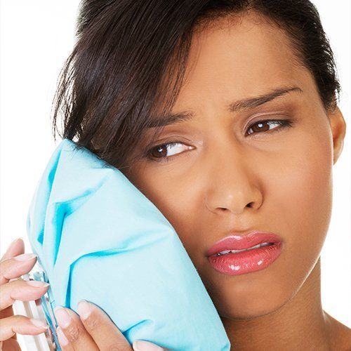 woman holding ice bag to cheek