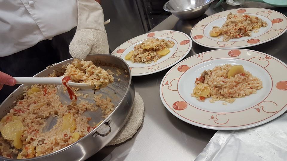 una mano con un cucchiaio che serve dei piatti di risotto