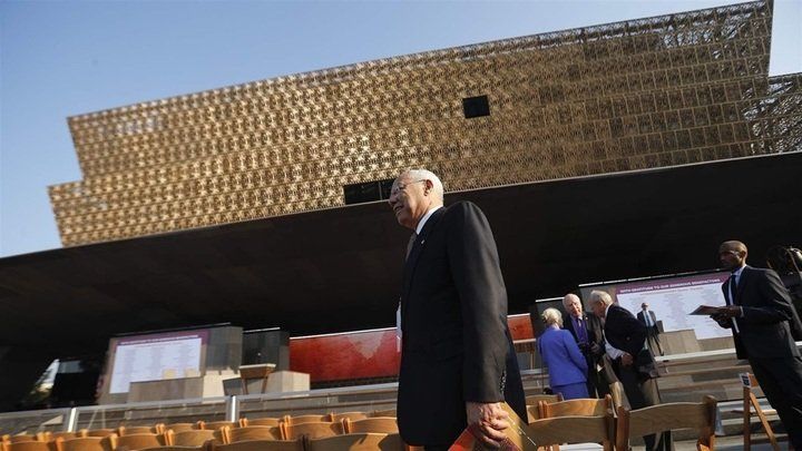a man in a suit is walking in front of a large building