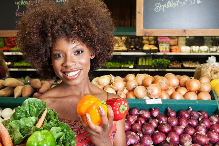 a woman in a grocery store holding a pepper