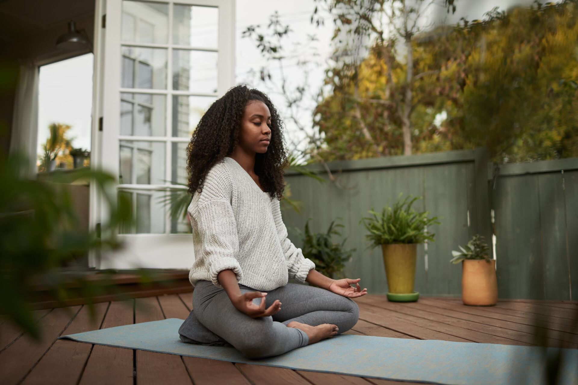 a woman is sitting on a yoga mat on a deck .