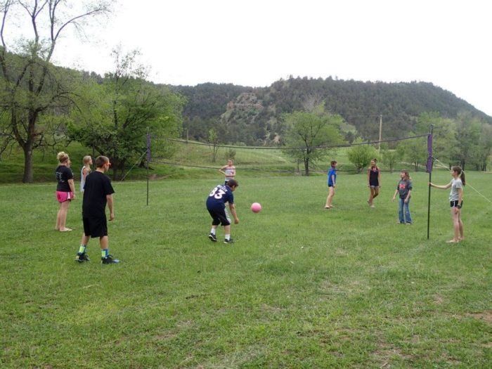A group of children are playing volleyball in a grassy field at Allen Ranch Campground Hot Springs SD