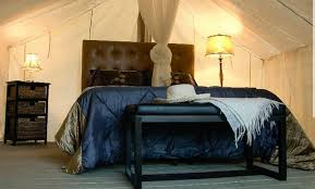 A bed with a blue comforter and a cowboy hat on it in a tent.