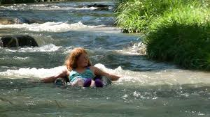 A woman is floating on a raft in a river at the Allen Ranch Campground.