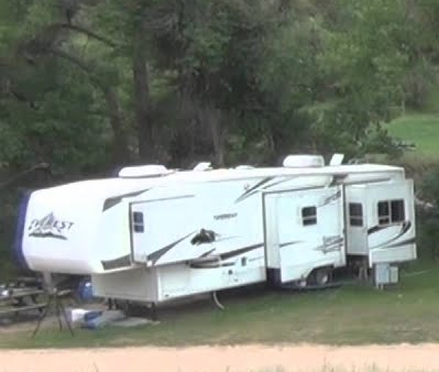 A white rv is parked in a grassy field.