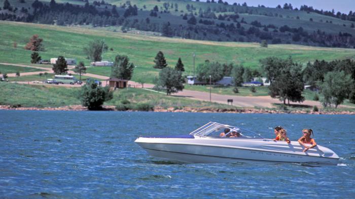Two people are riding a speed boat on a lake