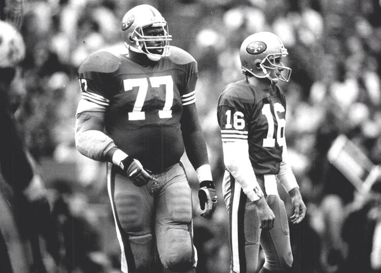 A black and white photo of two football players wearing numbers 77 and 16