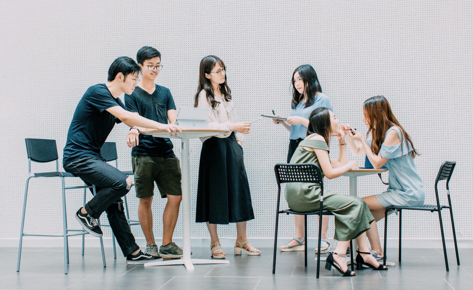 A group of people are sitting around a table talking to each other.