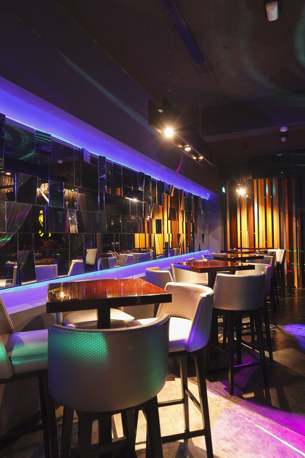 Un restaurante con mesas y sillas y luces violetas.