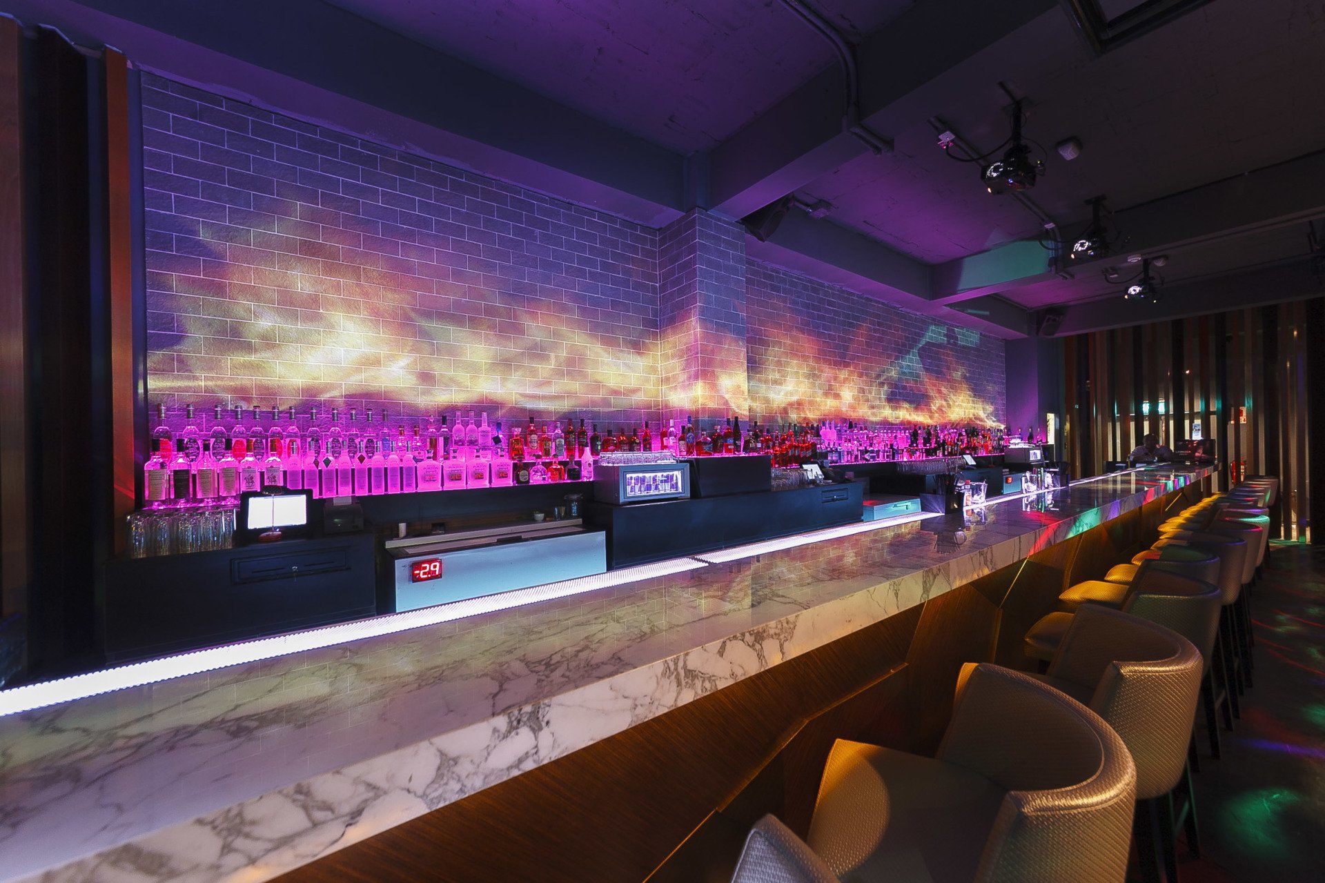 Un bar con un mostrador largo y sillas en una discoteca.
