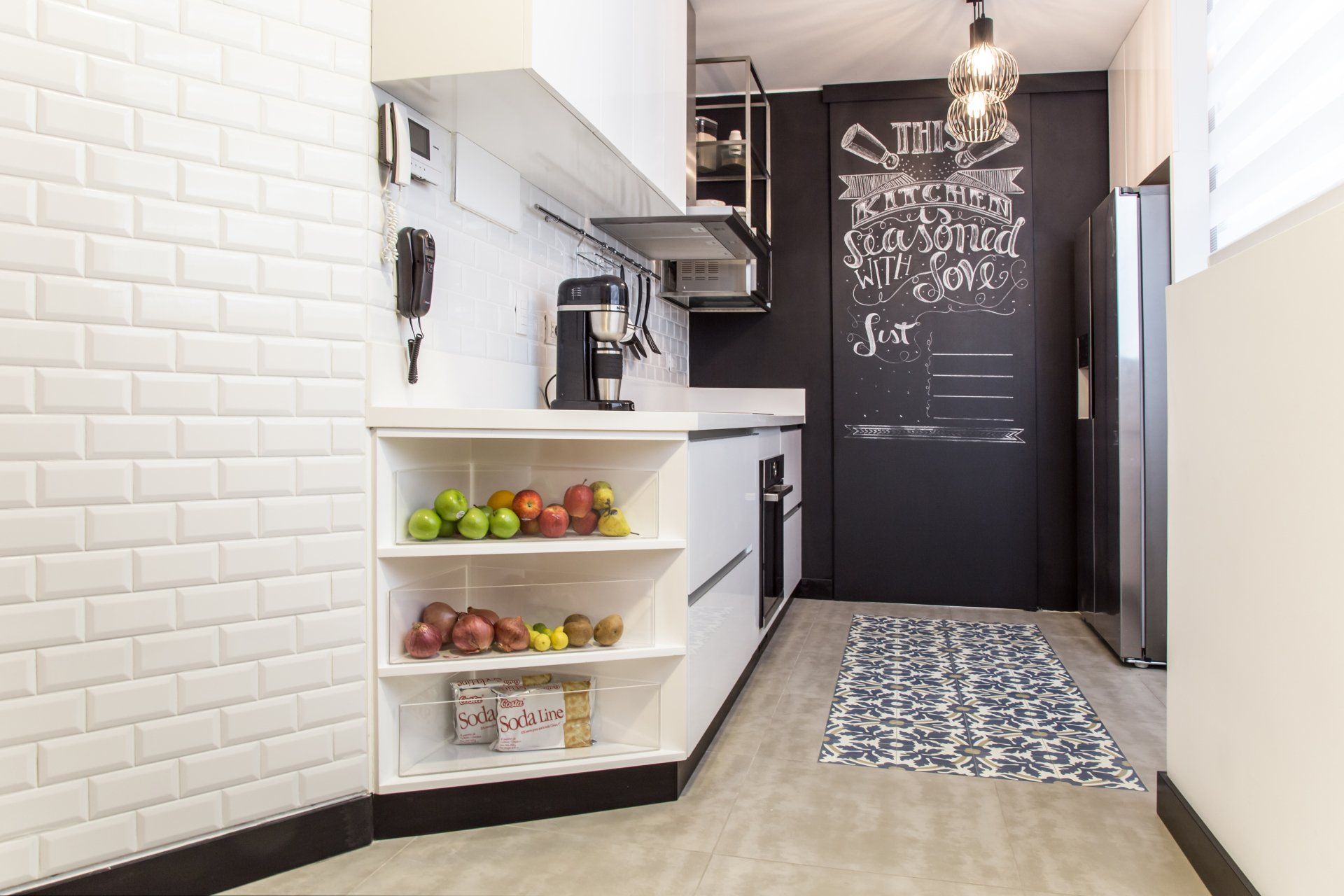 Una cocina con una pizarra en la pared y fruta en los estantes.