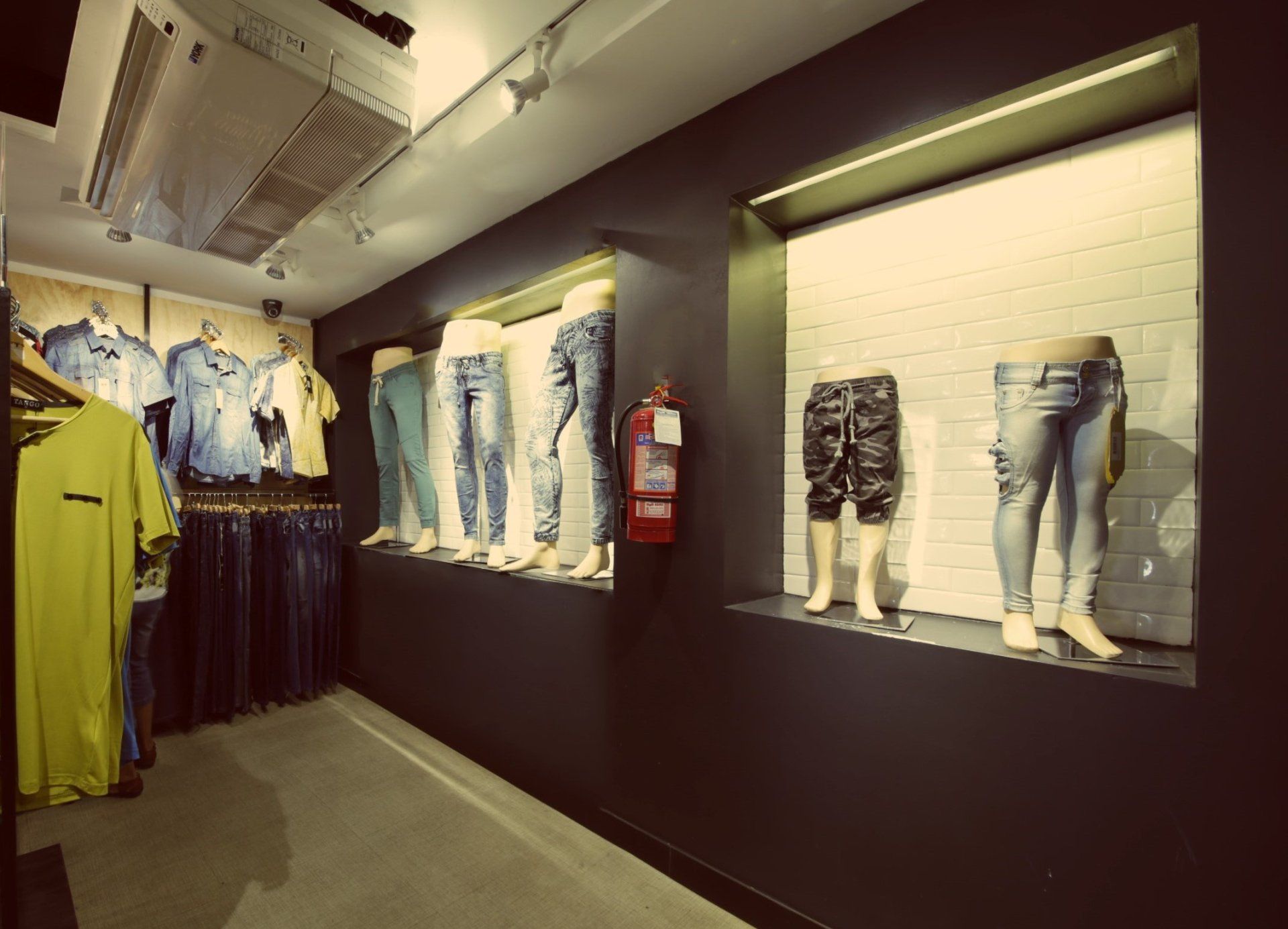 Una tienda llena de ropa y maniquíes y un extintor de incendios.