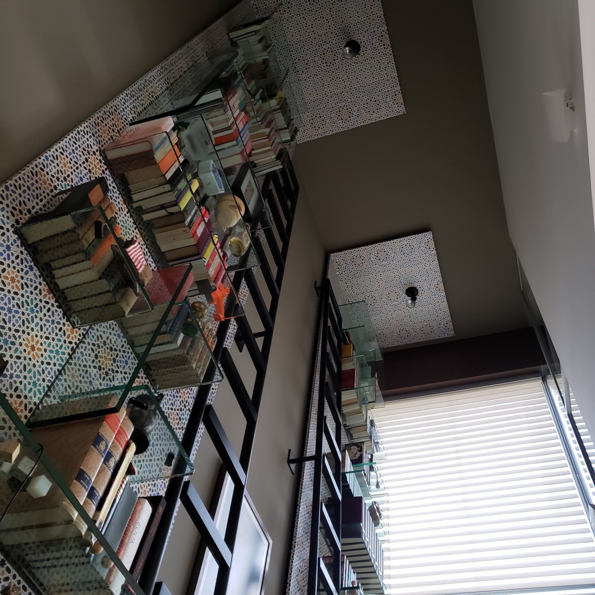 Un estante de cristal lleno de libros y una escalera.