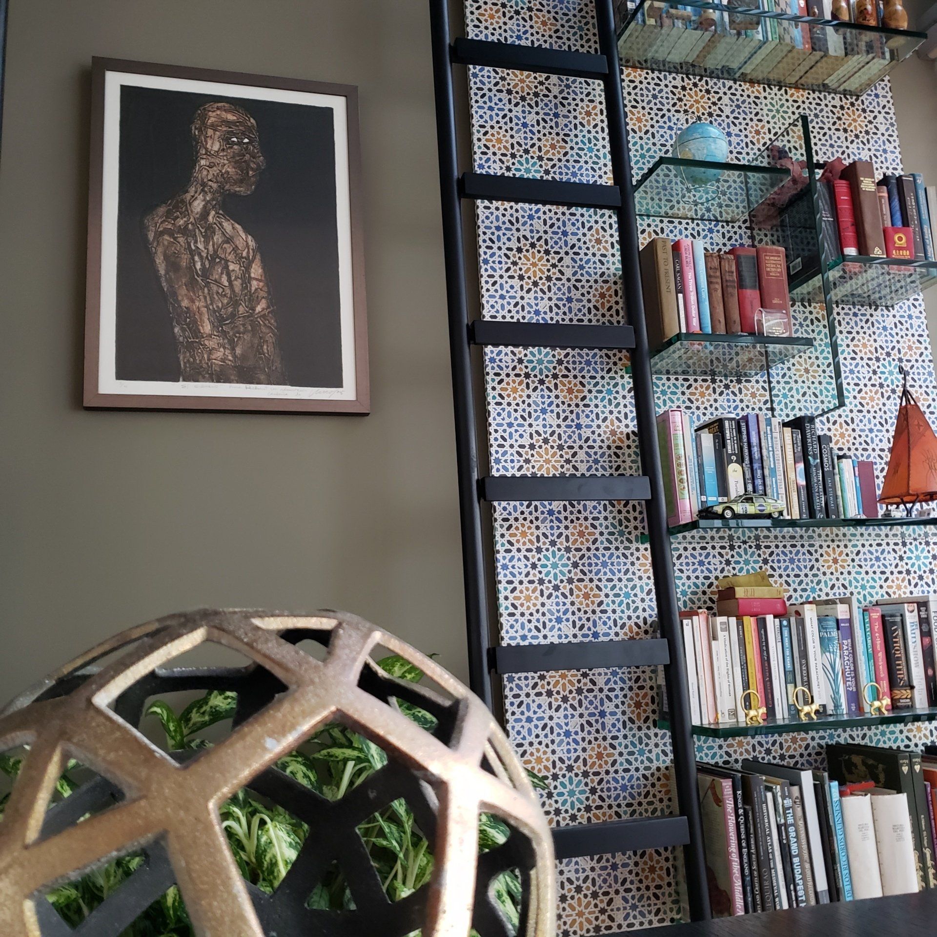 Una estantería con una escalera y un cuadro en la pared.