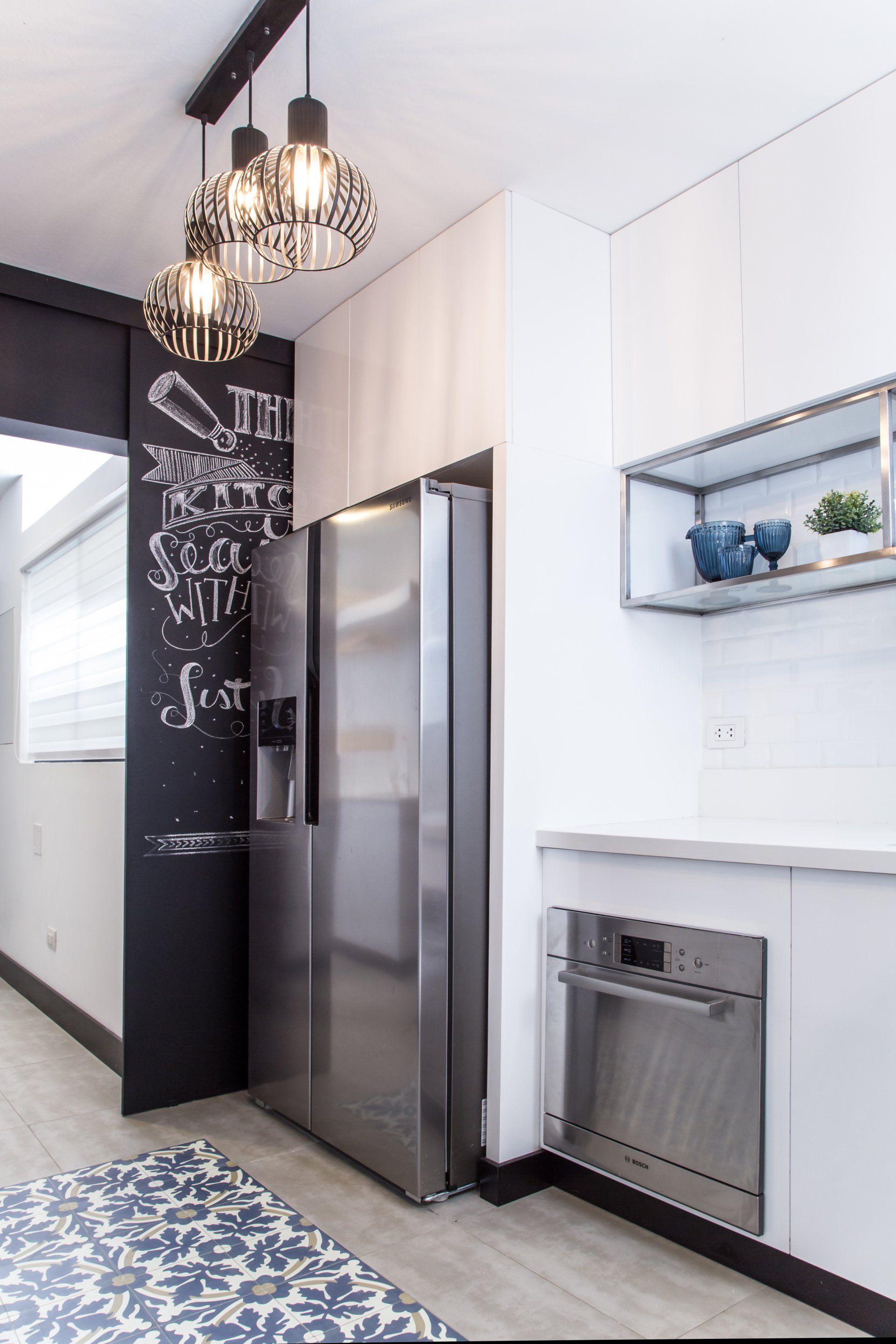 Una cocina con refrigerador de acero inoxidable y una pizarra en la pared.