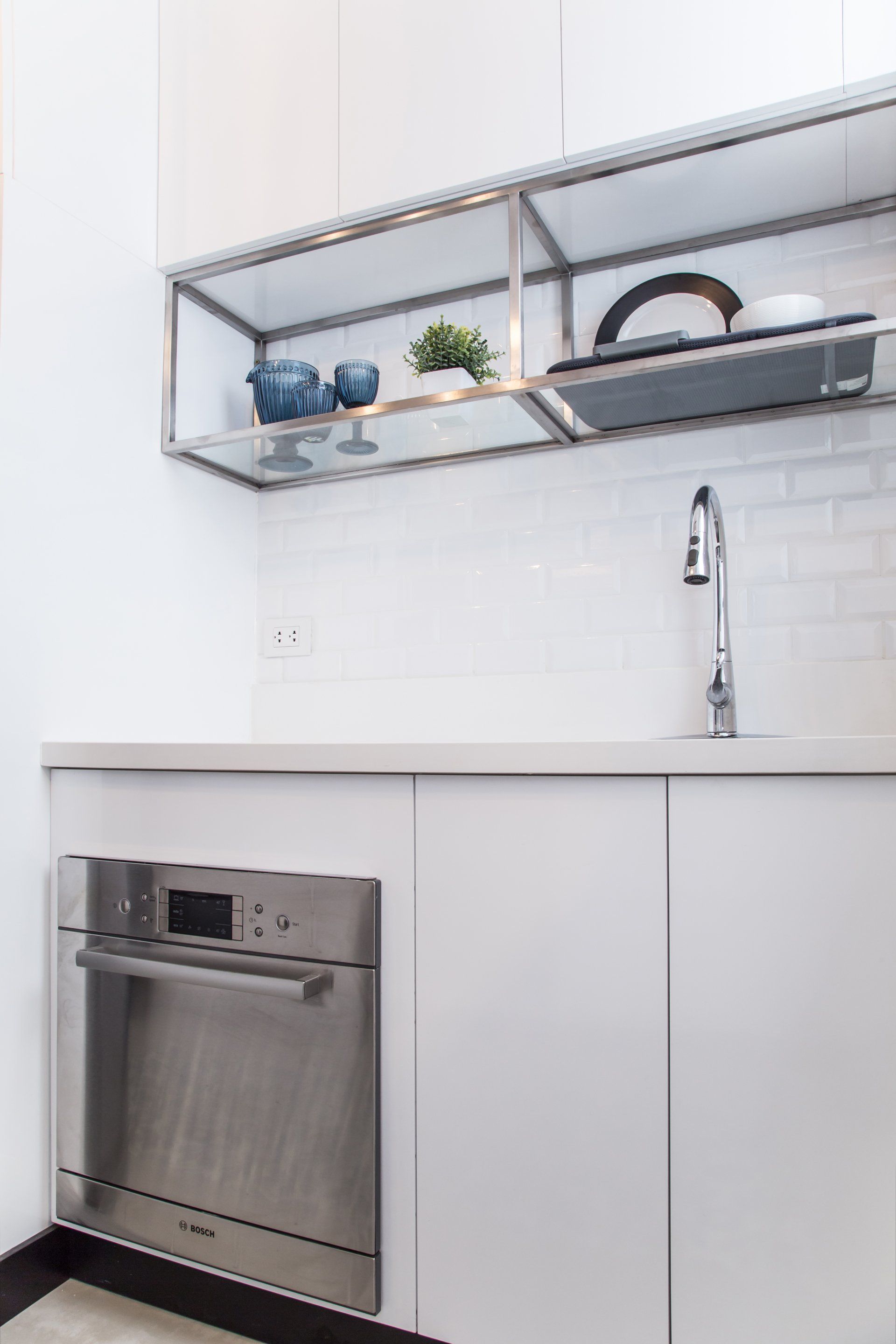 Una cocina con gabinetes blancos y lavavajillas de acero inoxidable.