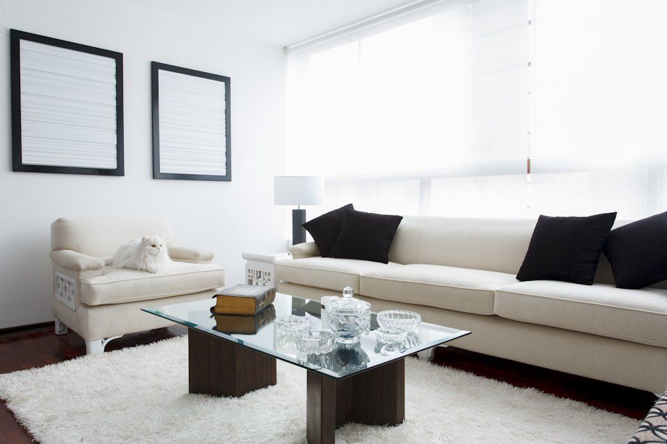 Una sala de estar con un sofá blanco y una mesa de café de cristal.