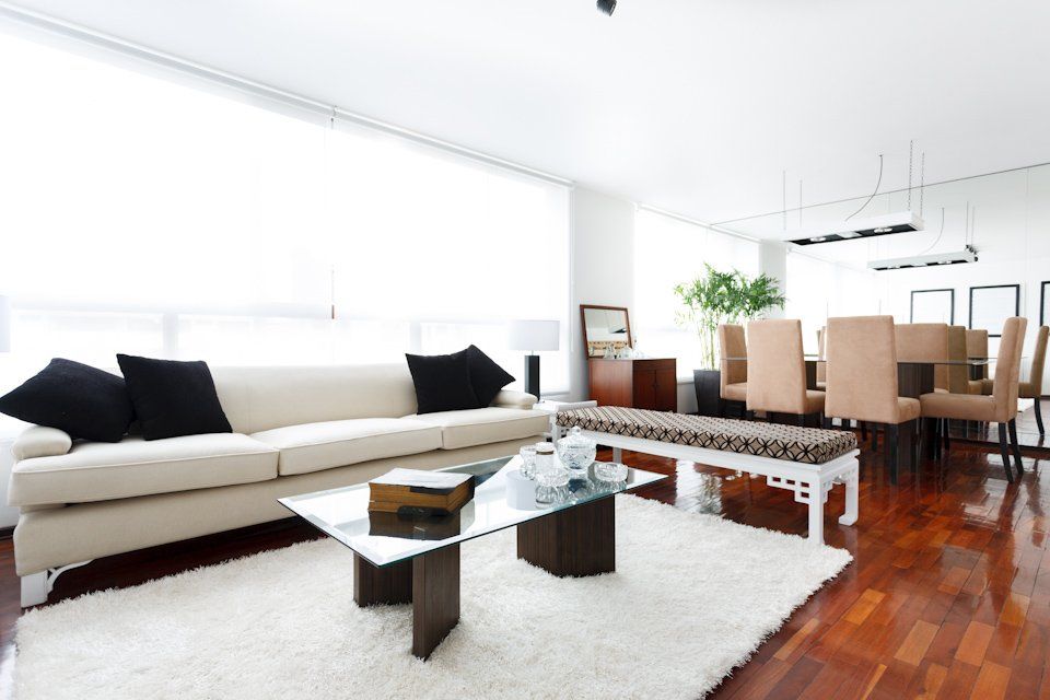 Una sala de estar con un sofá blanco y una mesa de café de cristal.