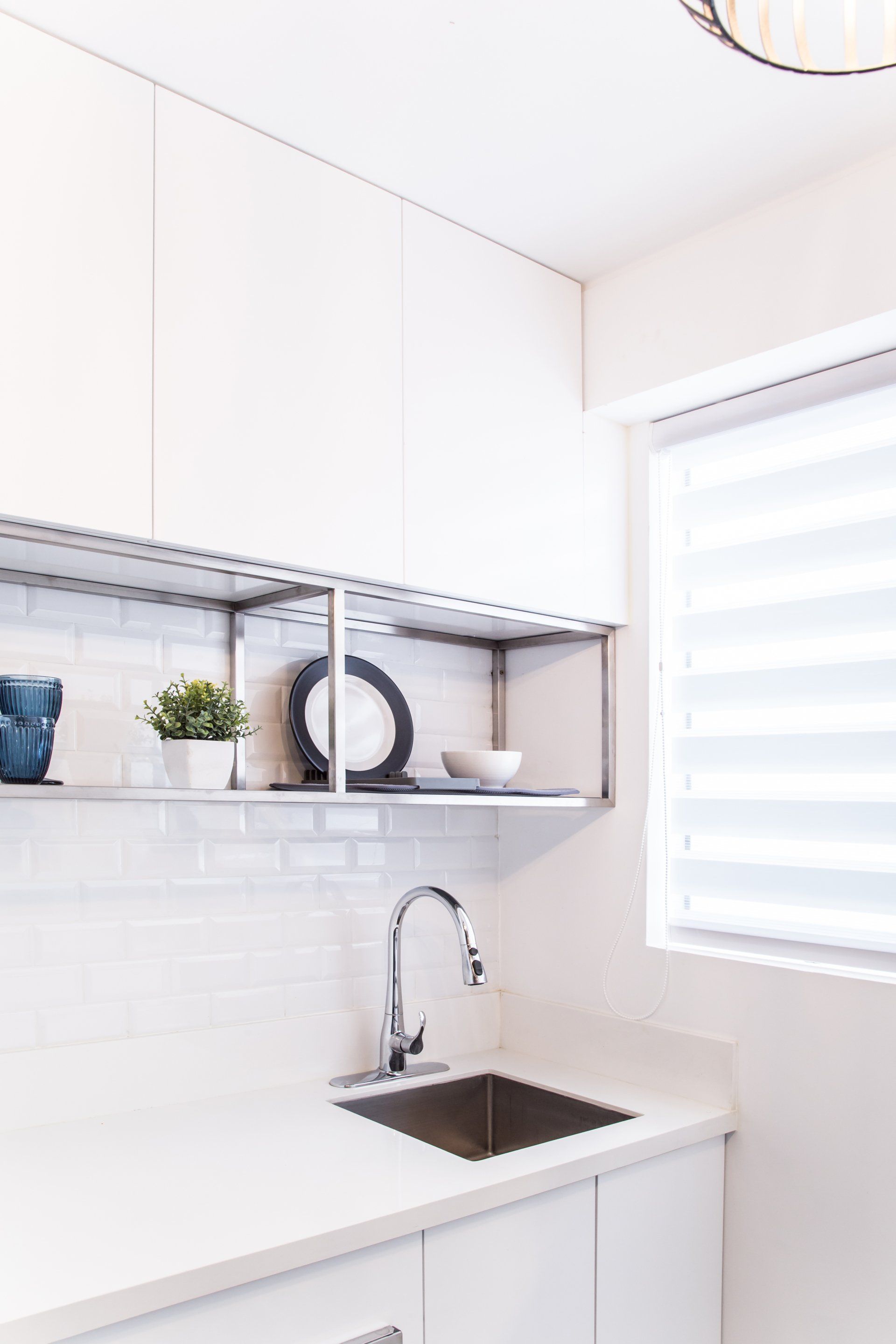 Una cocina con fregadero, estantes y una ventana.