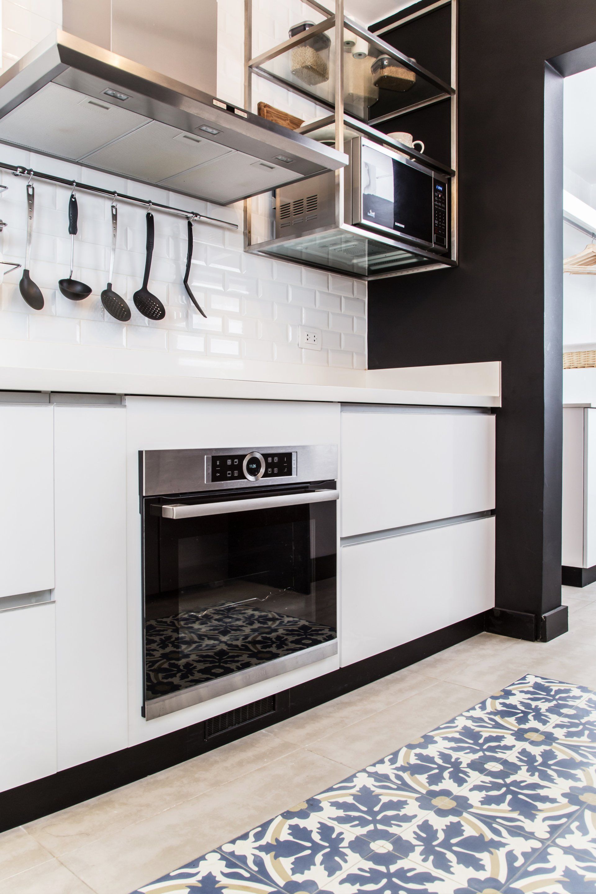 Una cocina con muebles blancos y un horno de acero inoxidable.
