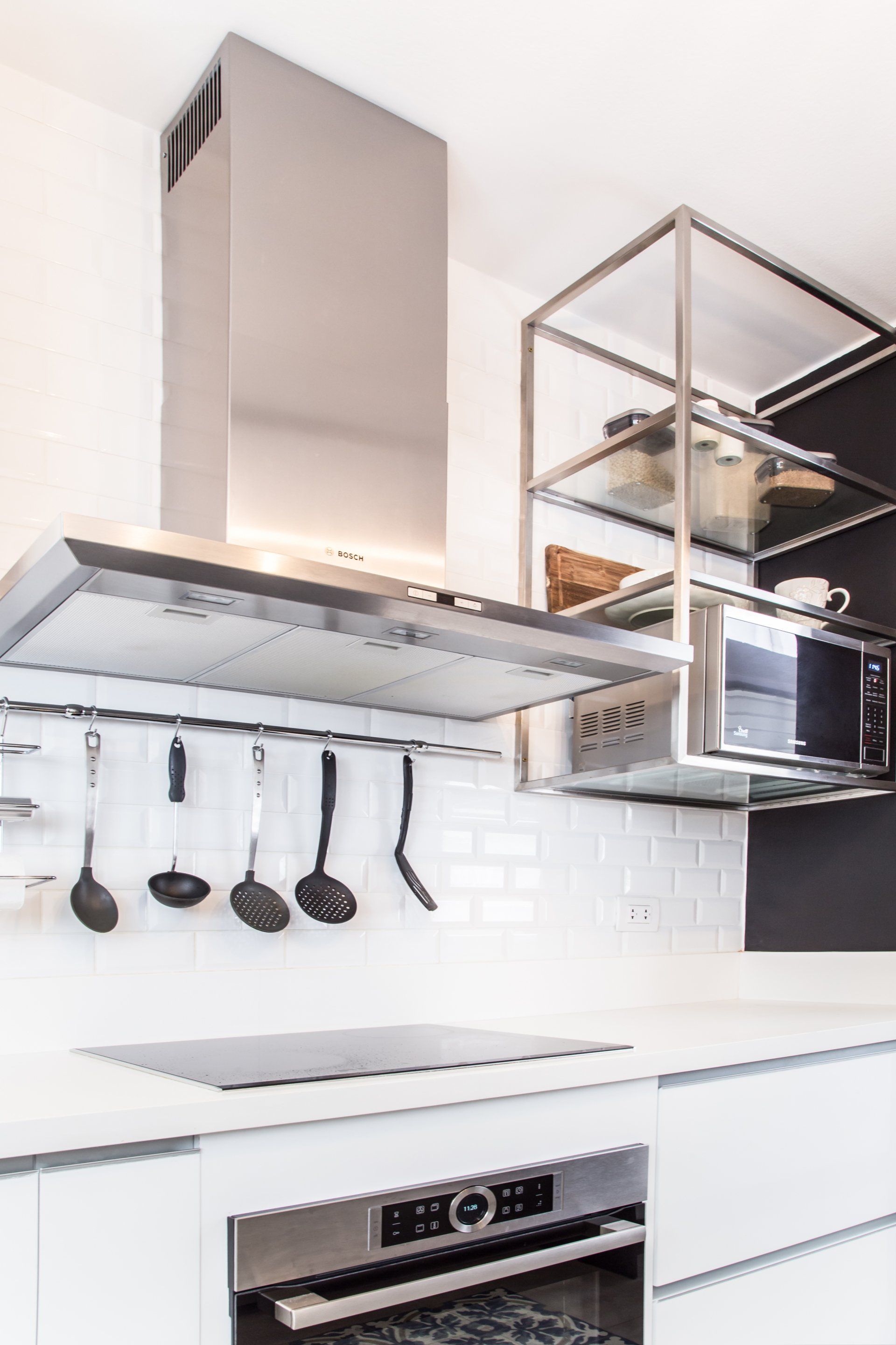 Una cocina con electrodomésticos de acero inoxidable y utensilios colgados del techo.