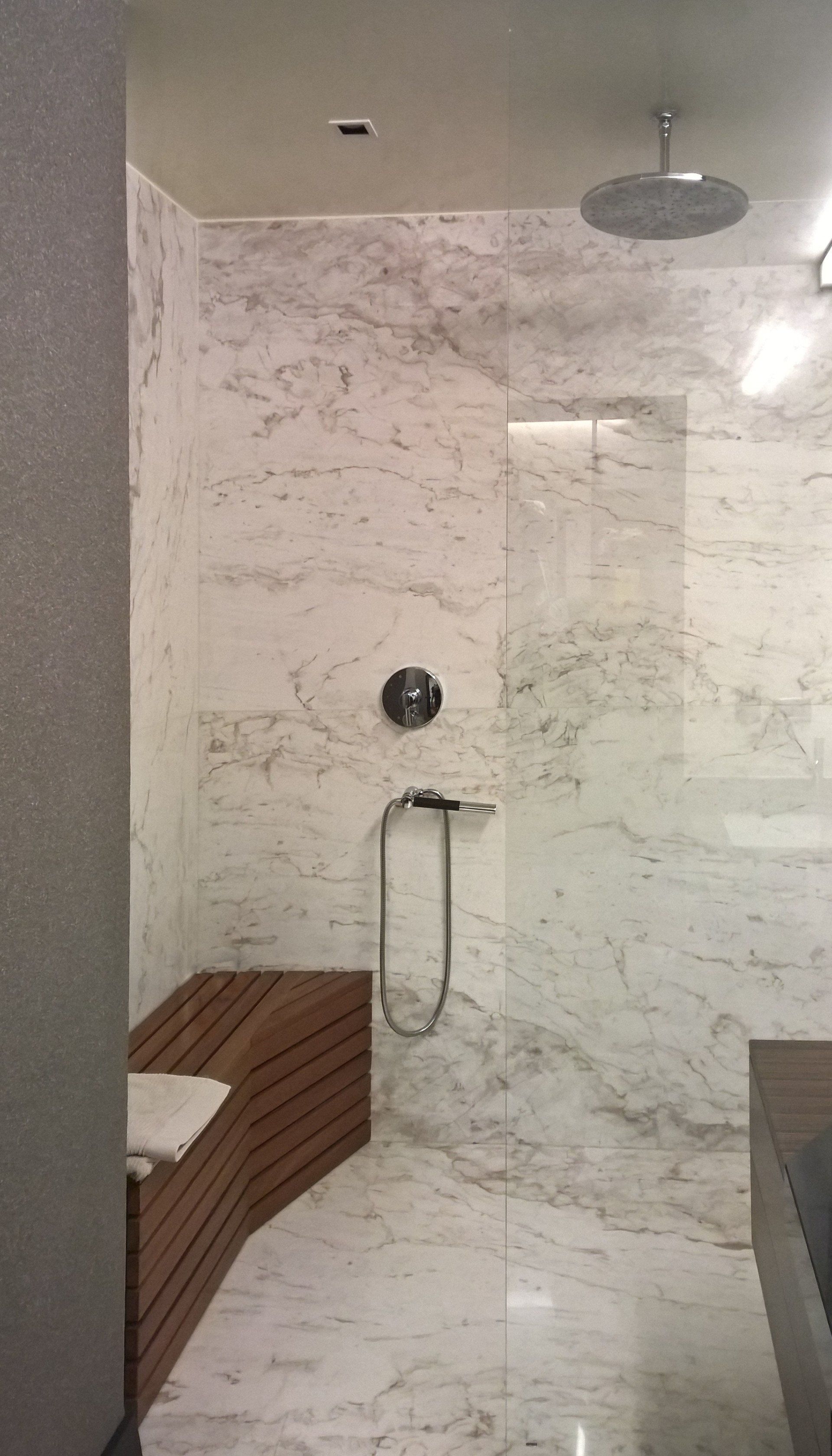 Un baño con ducha a ras de suelo y un banco de madera.