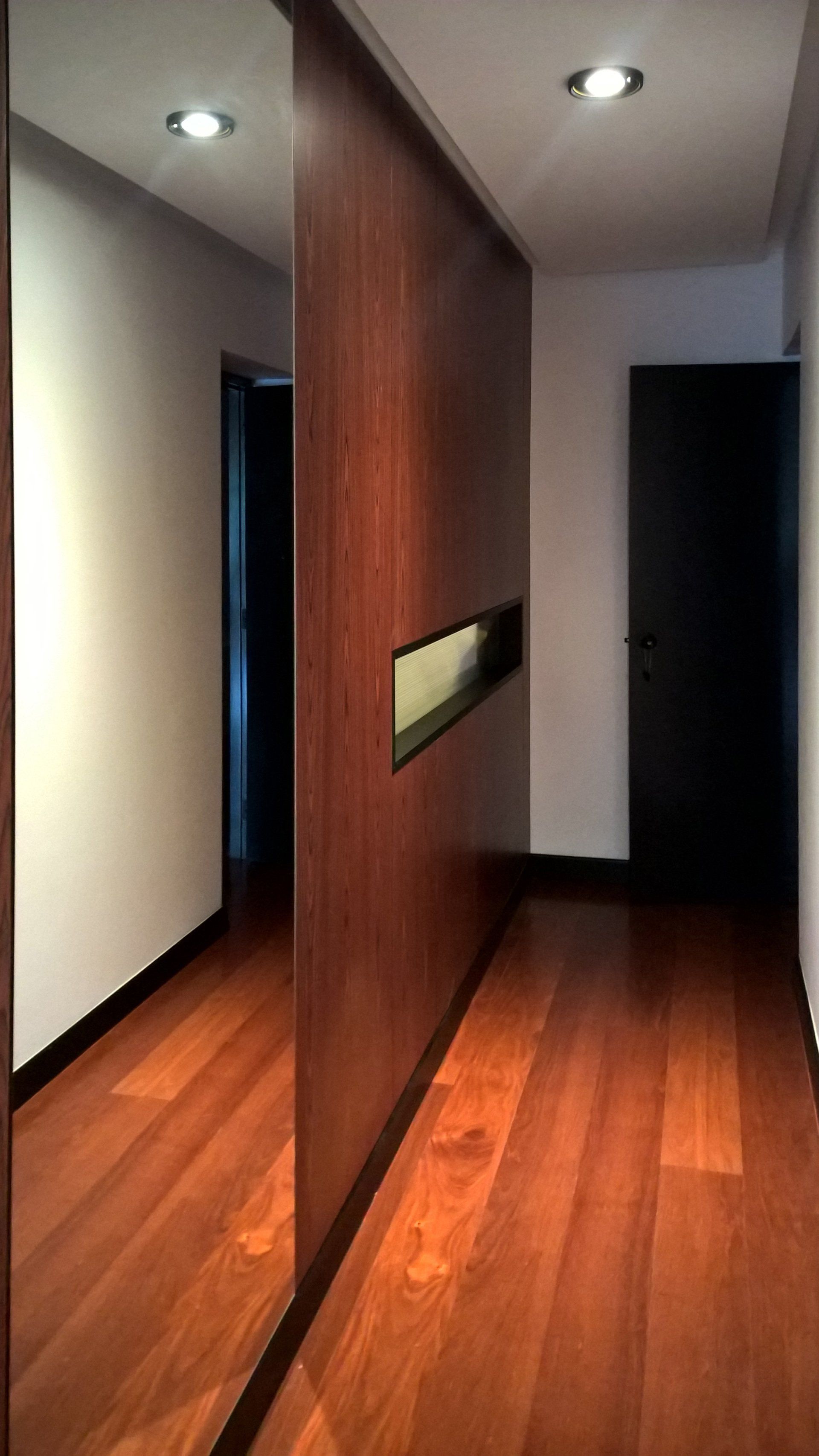Un pasillo con pisos de madera y un espejo en la pared.